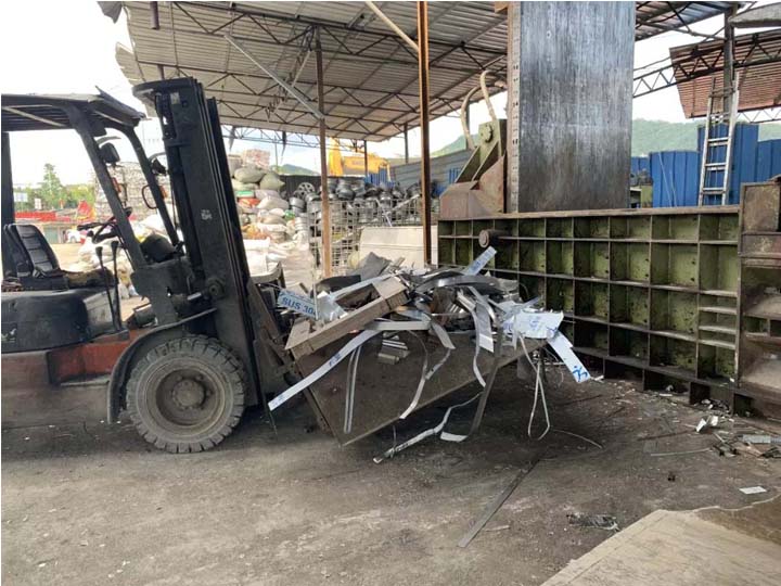 Forklift is putting material into a scrap metal briquette machine